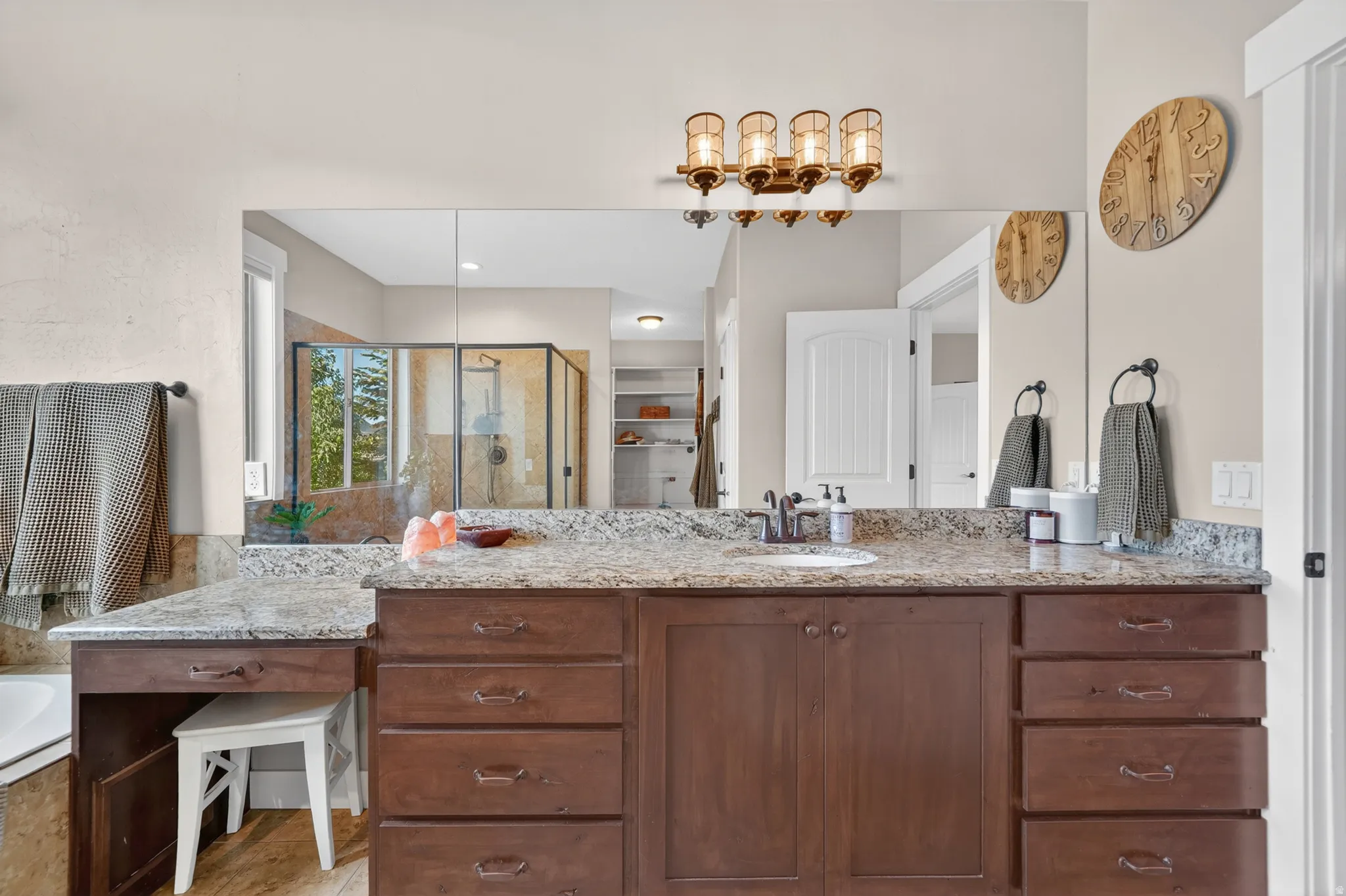 Spacious vanity featuring a light granite countertop, dark wood-finish cabinetry, a built-in makeup area, and an integrated sink with a dark-finish faucet