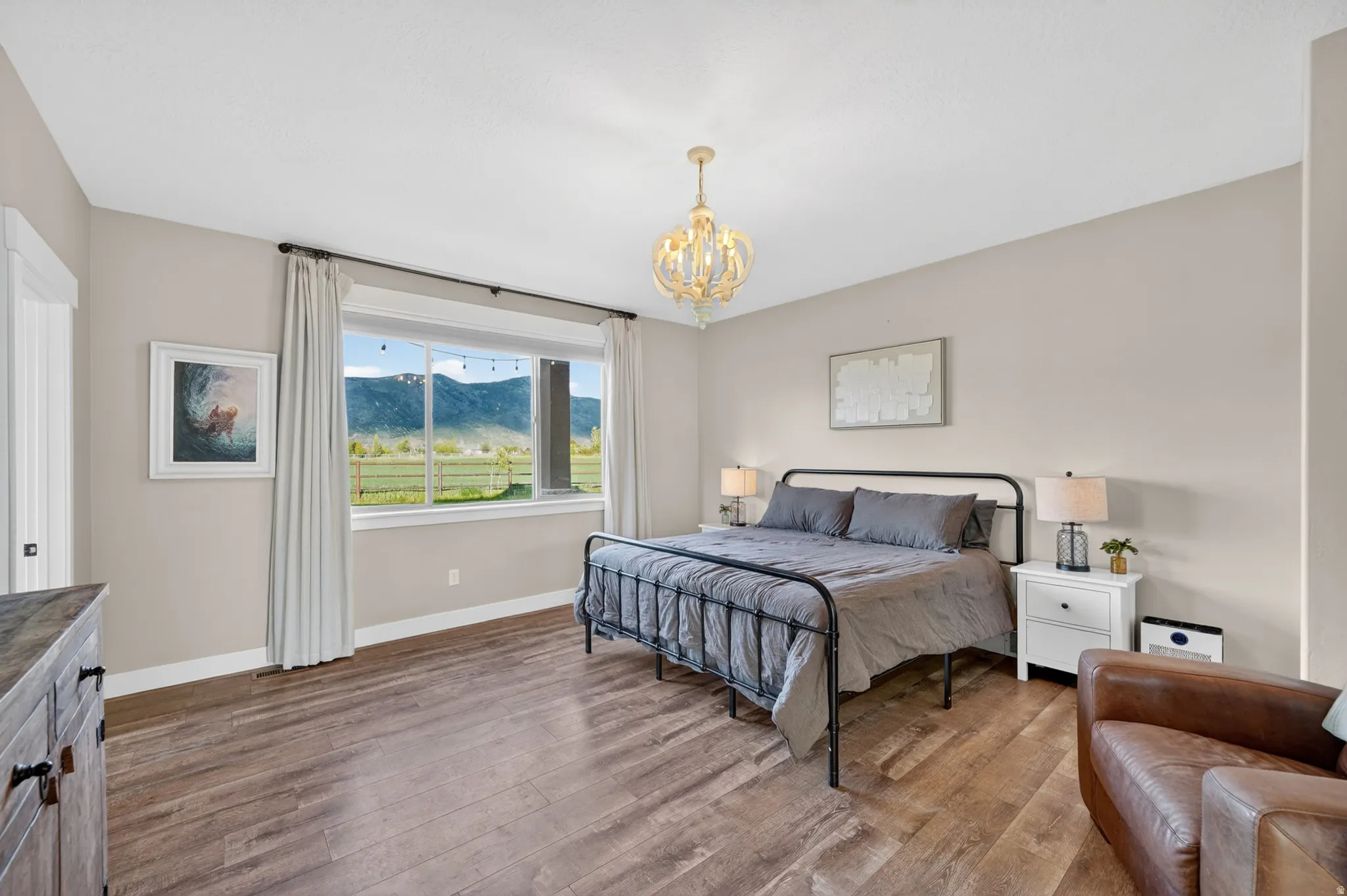 Bedroom featuring wood-finish flooring, a contemporary chandelier, neutral wall tones, and a large picture window