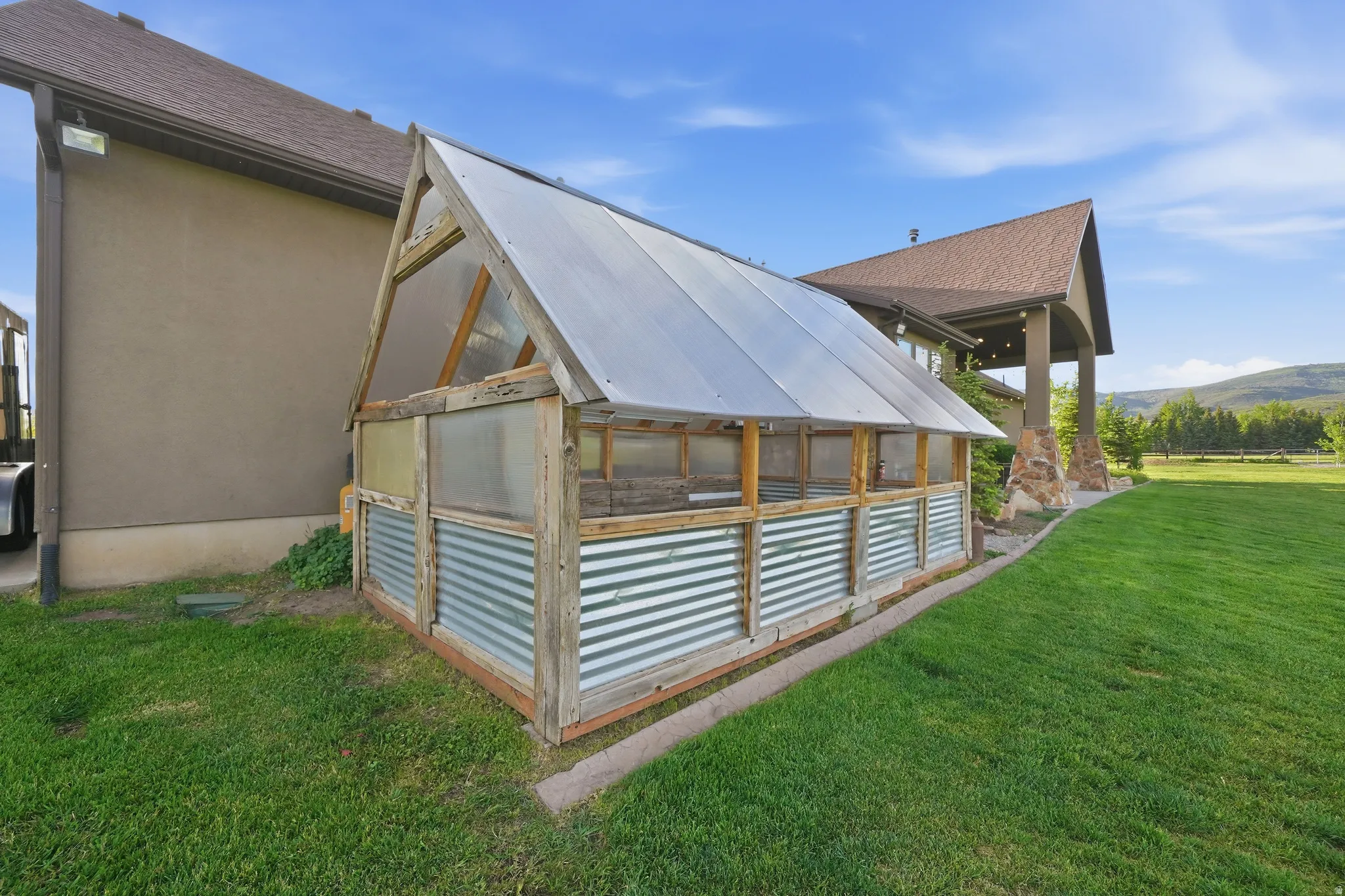 Gable-roof greenhouse featuring corrugated metal and translucent paneling
