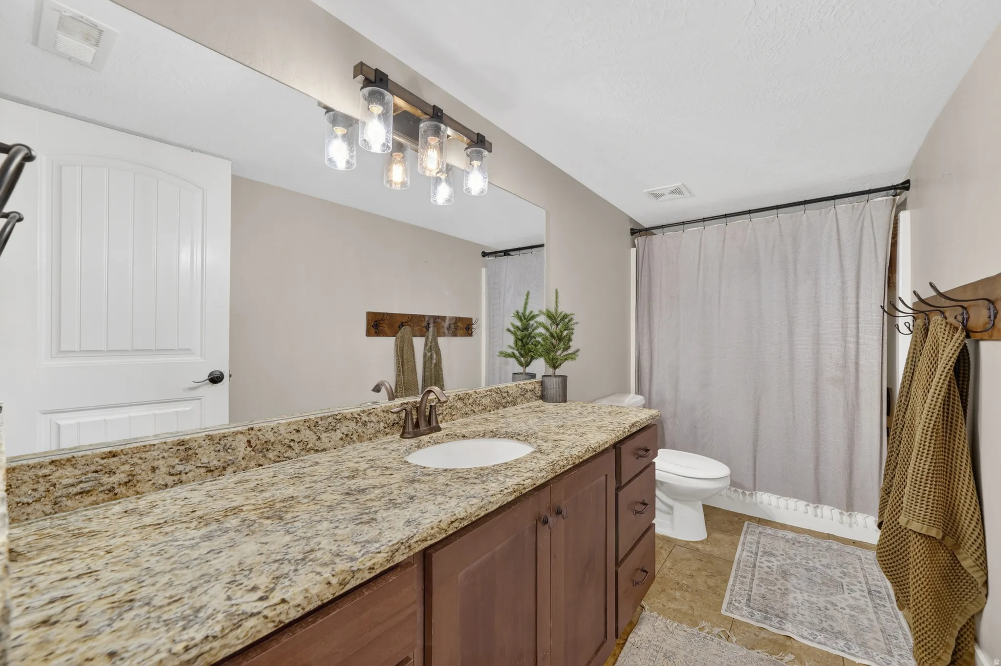 Bathroom featuring an extended vanity with a light-colored speckled countertop, an undermount sink, and a bronze-finish faucet
