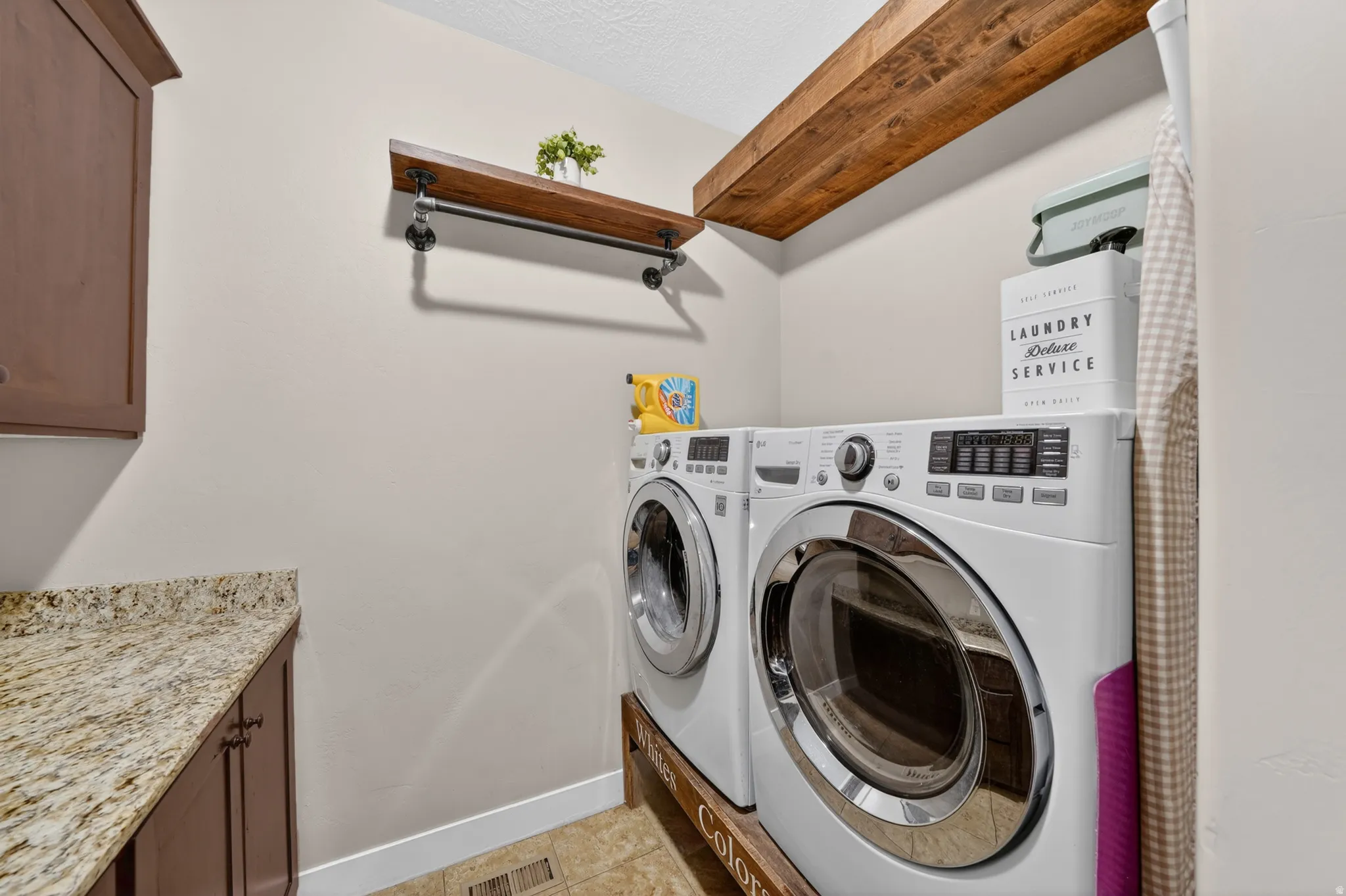 Laundry area featuring built-in cabinetry, stone-finish countertops, wood-finish shelving, and wood-finish flooring