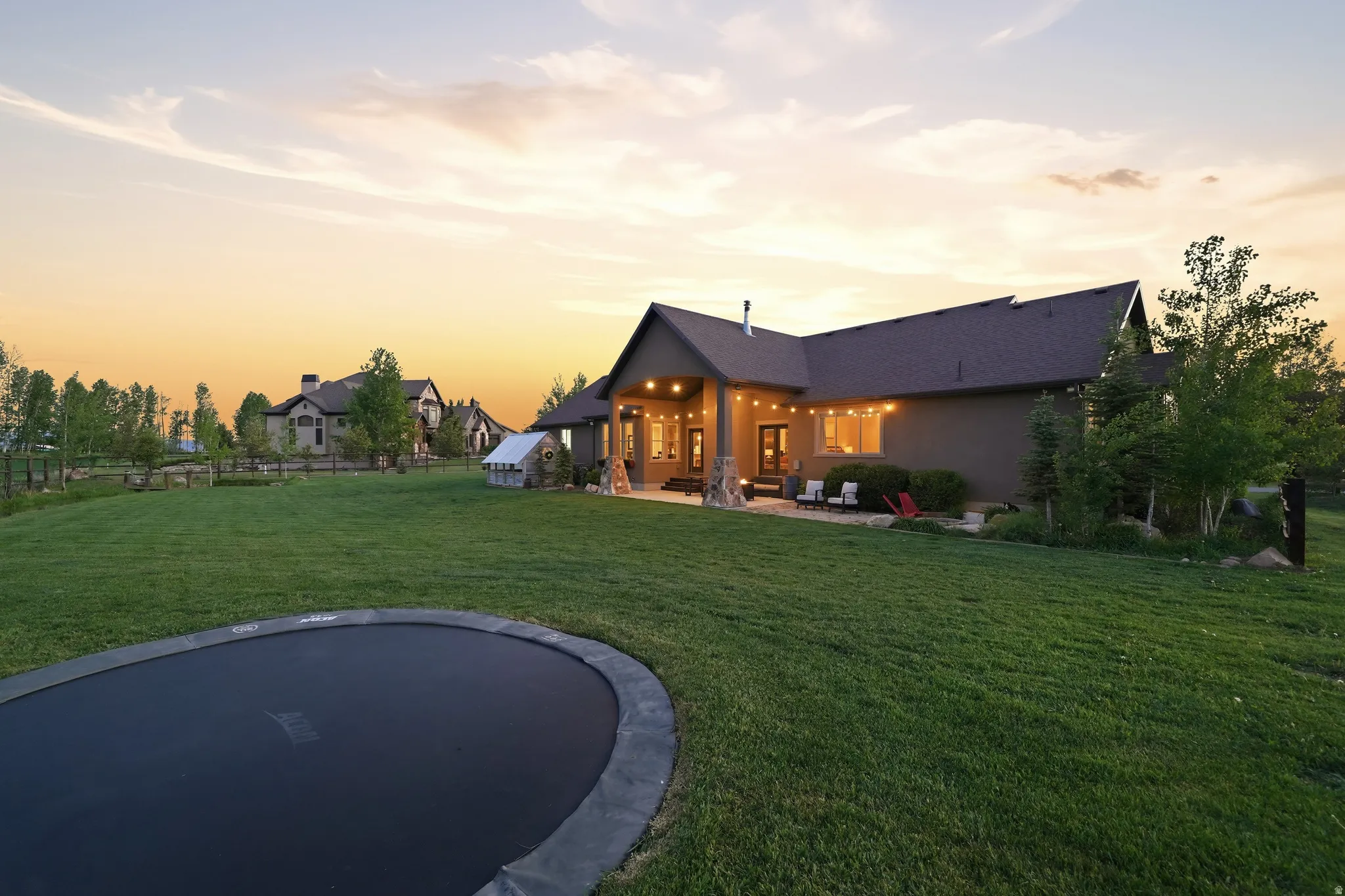 Expansive green lawn with mature trees and a built-in trampoline