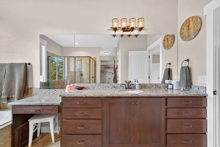 Spacious vanity featuring a light granite countertop, dark wood-finish cabinetry, a built-in makeup area, and an integrated sink with a dark-finish faucet