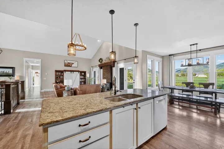 Kitchen island featuring a dual basin sink, integrated dishwasher, and granite-finish countertop