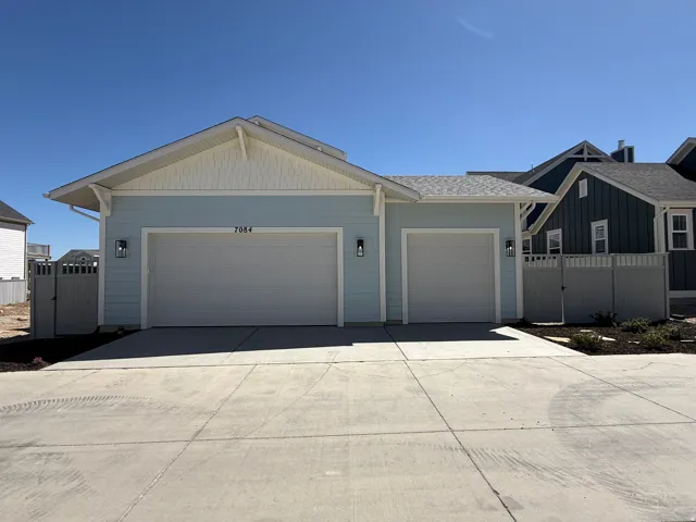 Coastal-inspired exterior featuring light blue siding with white trim, a double garage, and a concrete driveway