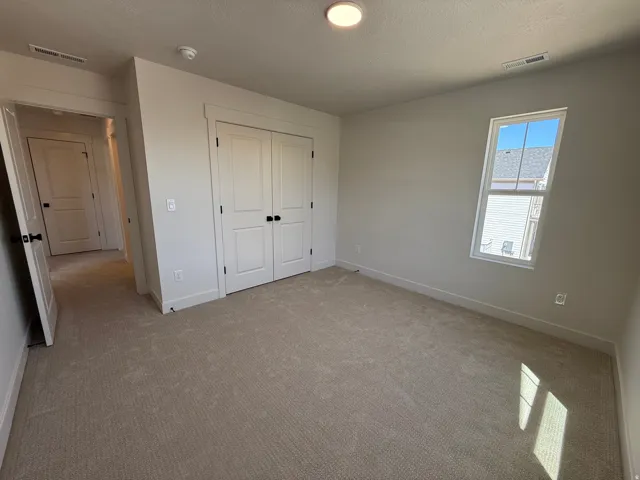 Neutral-toned carpeted interior space featuring a double-door closet, a single window, and recessed lighting