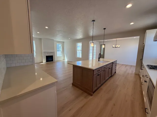 Open-concept kitchen and living area featuring wood-finish flooring, recessed lighting, and a kitchen island with pendant lights