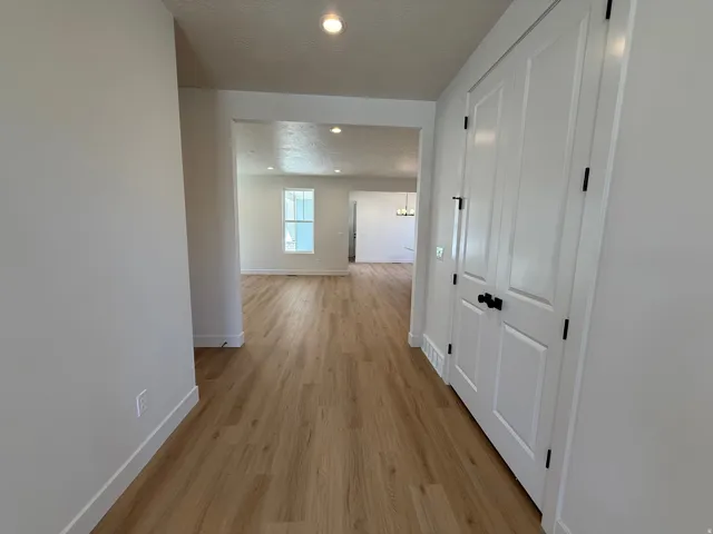 Inviting hallway featuring wood-finish flooring, white walls, and bright recessed lighting