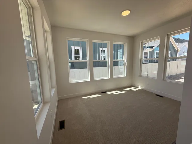Bright room featuring ample natural light, neutral carpet flooring, white walls, and multiple large windows