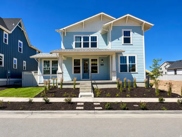 Two-story light blue residence featuring white trim details and a covered front porch