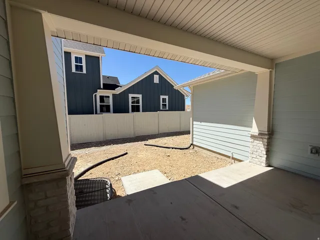 Covered concrete patio featuring a stone-clad column base and light blue siding