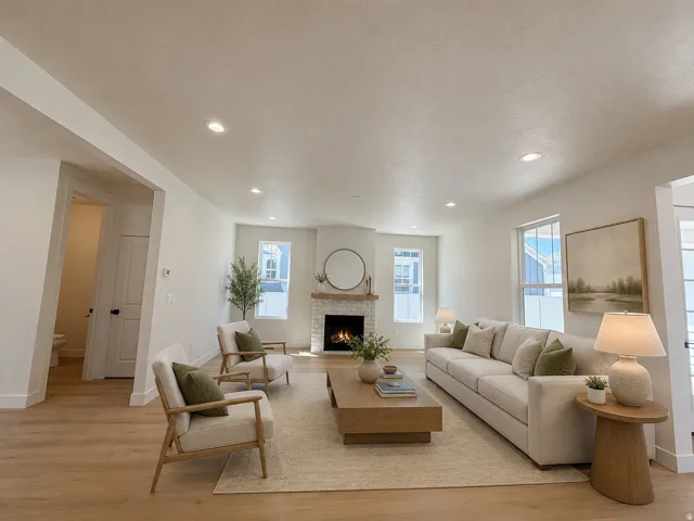 Living area featuring light wood-finish flooring, recessed lighting, and a stone-clad fireplace with a wood mantel