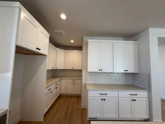 Modern kitchen featuring extensive white shaker cabinetry, light-toned countertops, and a white subway tile backsplash