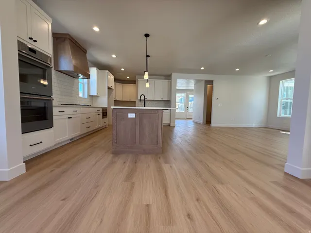 Open-concept kitchen and living area featuring wood-finish flooring, recessed lighting, and a kitchen island with pendant lighting