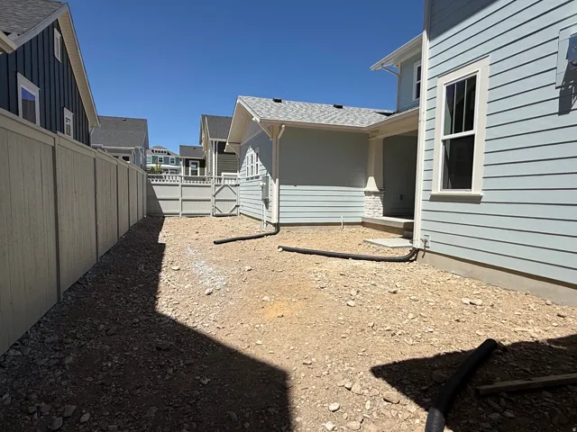 Side yard area featuring a light-toned privacy fence and direct access to the home