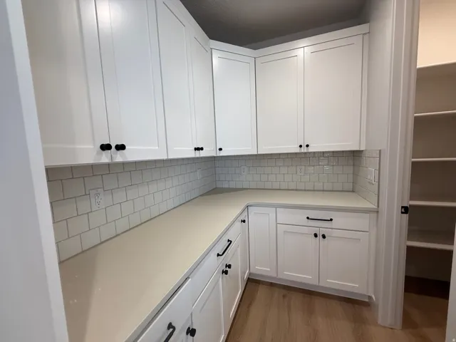 White shaker cabinetry with matte black hardware, light-toned countertops, and a white subway tile backsplash