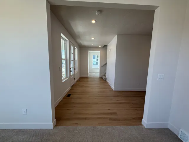 Expansive entryway featuring wood-finish flooring, recessed lighting, multiple windows, and a staircase with carpeted steps
