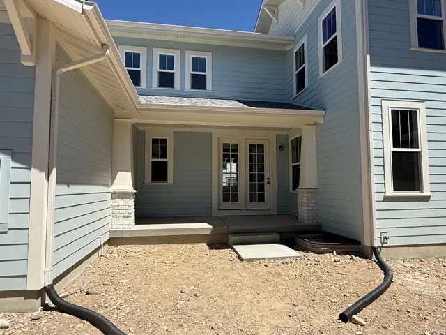 Light blue horizontal siding facade featuring white trim and a covered patio with columns accented by white stacked stone