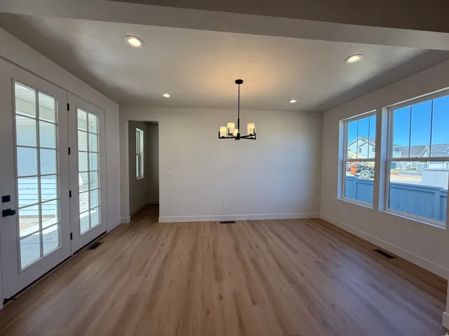 Spacious room featuring wood-finish flooring, white walls, and recessed lighting