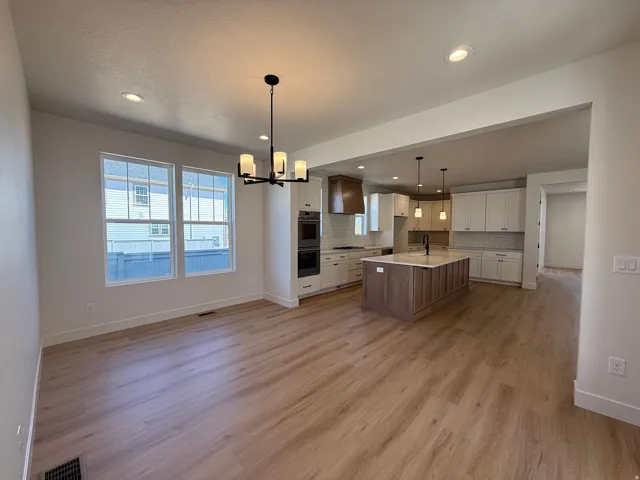 Open-concept living space featuring wood-finish flooring, recessed lighting, and a modern chandelier