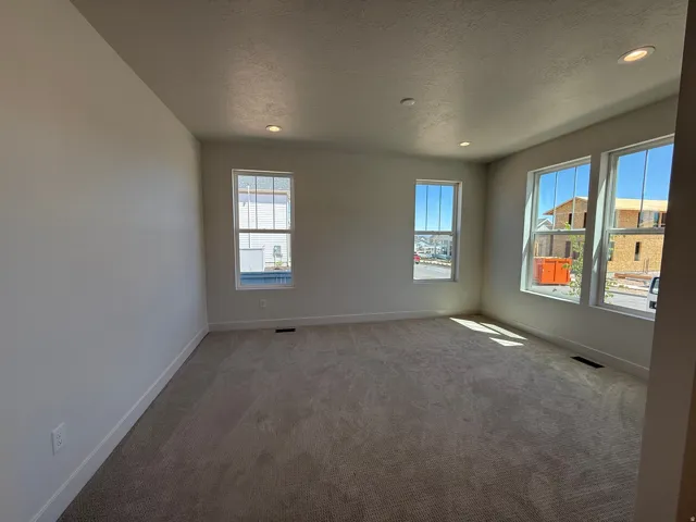 Spacious room featuring neutral carpet flooring, recessed lighting, and ample natural light from multiple windows