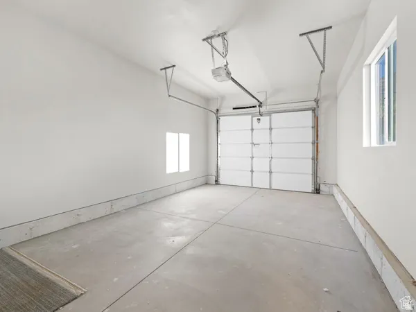 Spacious garage featuring a roll-up door, concrete flooring, high ceilings, and two windows providing natural light