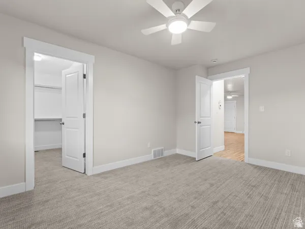 Neutral-toned room with plush carpeting and a white ceiling fan with integrated lighting