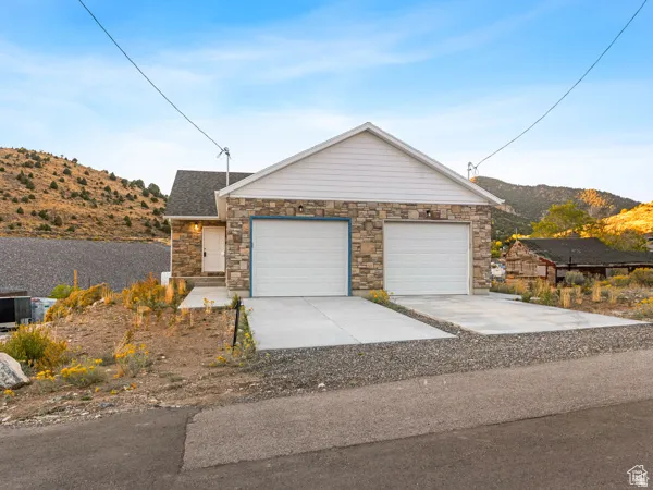 Stone veneer and siding exterior with a two-car garage, concrete driveway, and covered entry