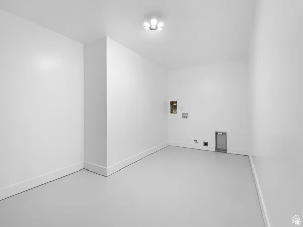 Utility room featuring bright white walls, white baseboards, a flush-mount ceiling light fixture, and light gray flooring