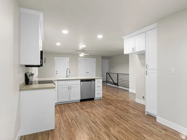 Contemporary kitchen featuring white cabinetry, light-toned countertops, and wood-finish flooring