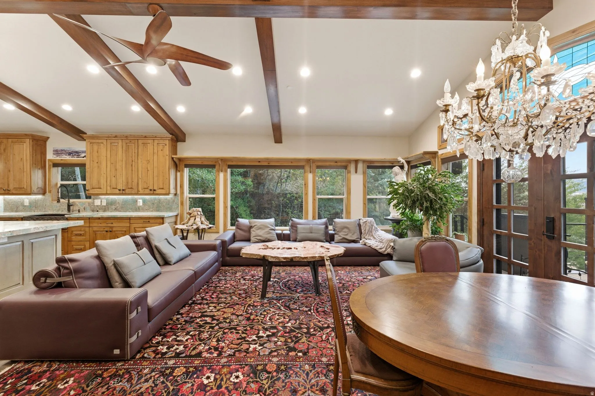 Expansive open-concept living area featuring a decorative chandelier, recessed lighting, and wood ceiling beams