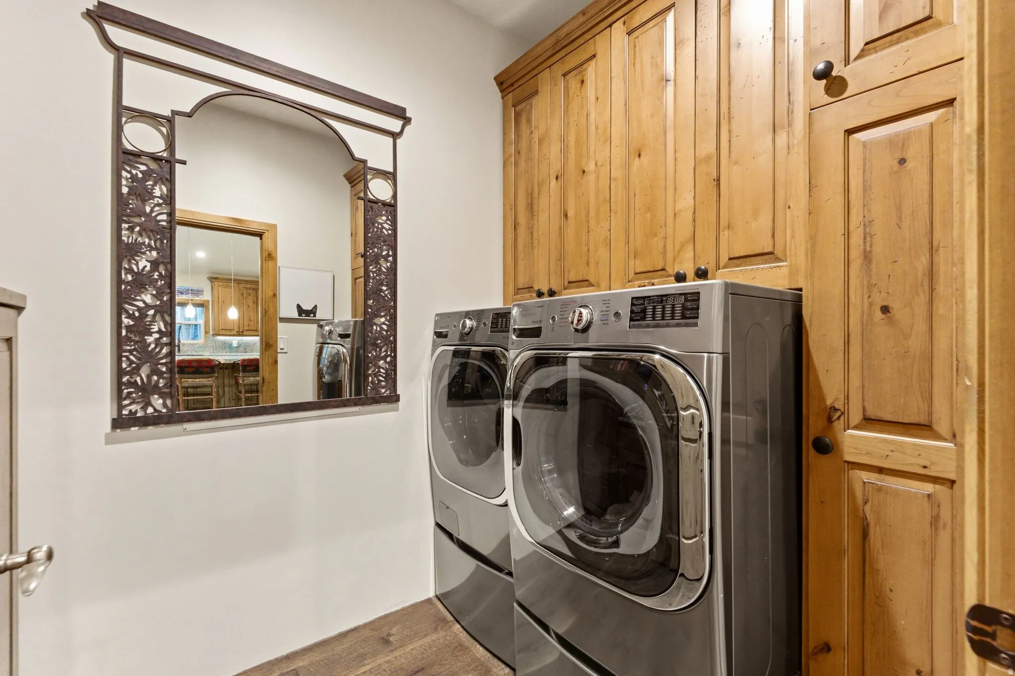 Utility area featuring extensive wood cabinetry, wood-finish flooring, and a decorative wall mirror