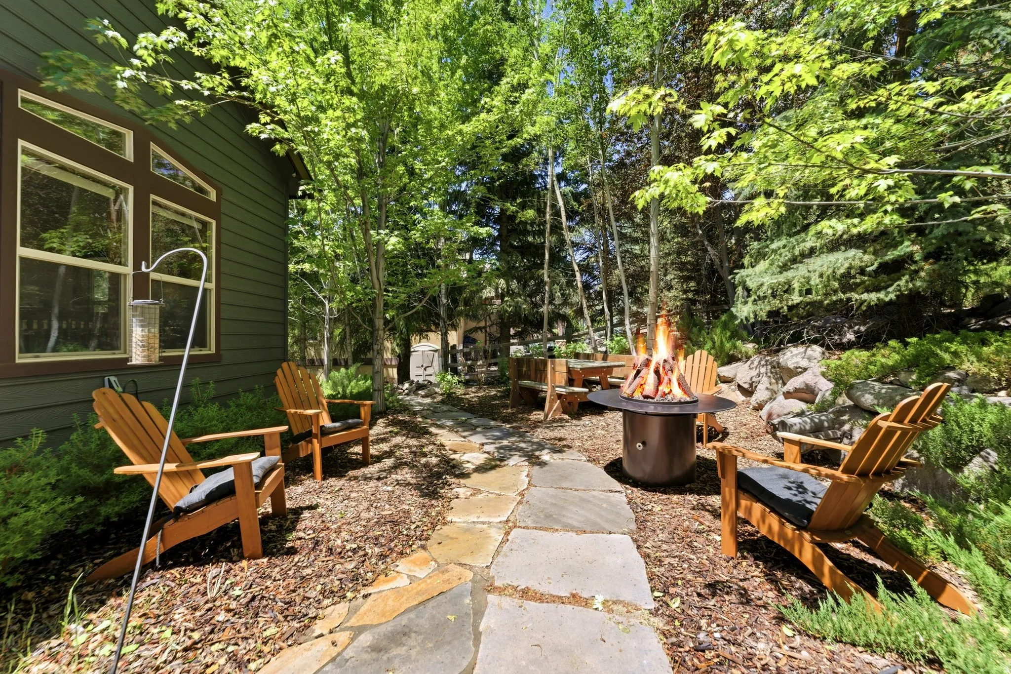 Outdoor stone pathway leading to a fire pit surrounded by Adirondack chairs