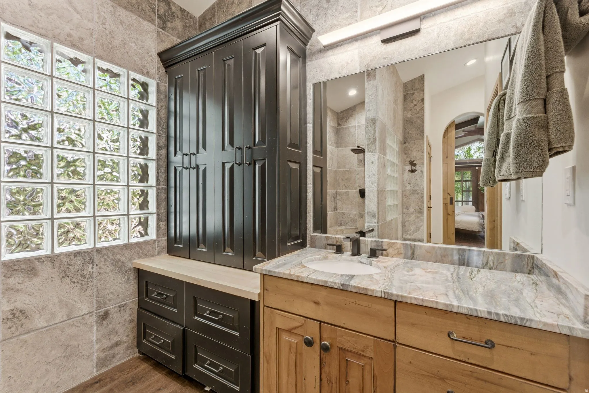 Bathroom featuring a dual-tone vanity with a stone countertop, an integrated sink, and an expansive mirror