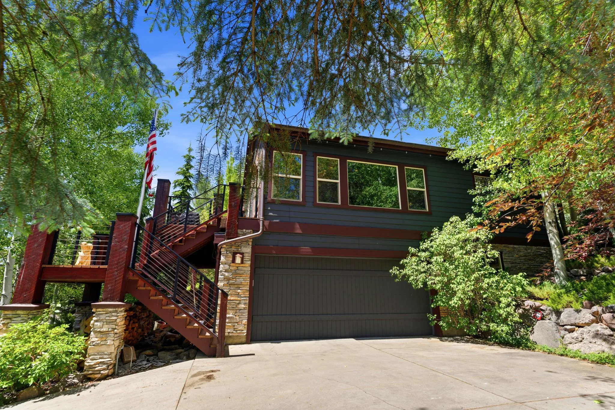 Multi-level residence featuring dark siding with contrasting trim, a two-car garage, and a concrete driveway