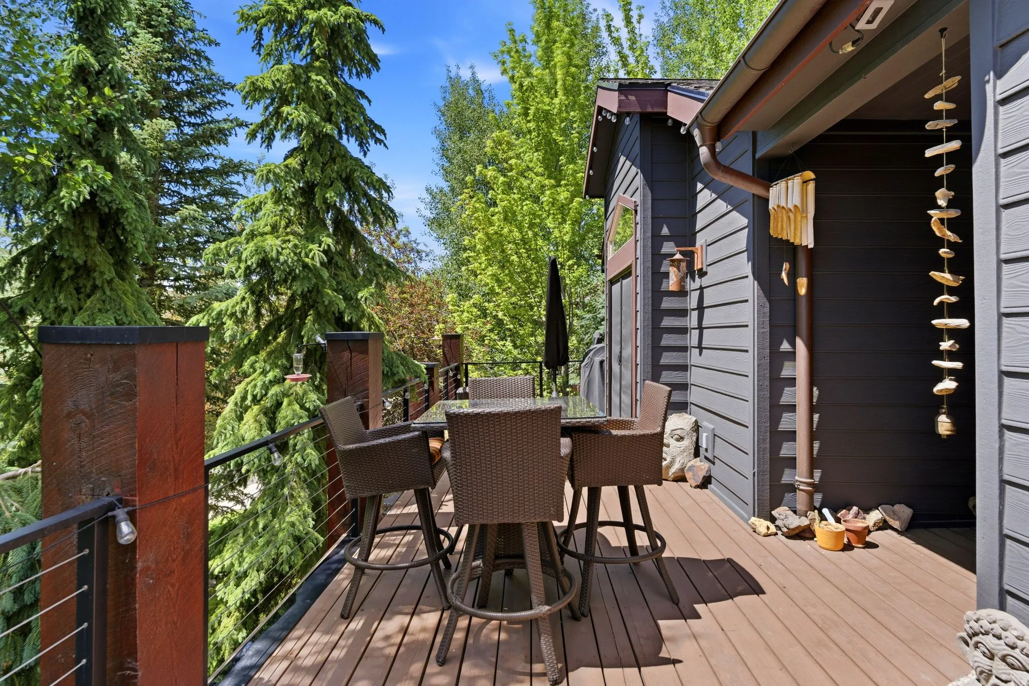 Expansive outdoor deck featuring wood-finish flooring, cable railing, and a dark-toned siding exterior