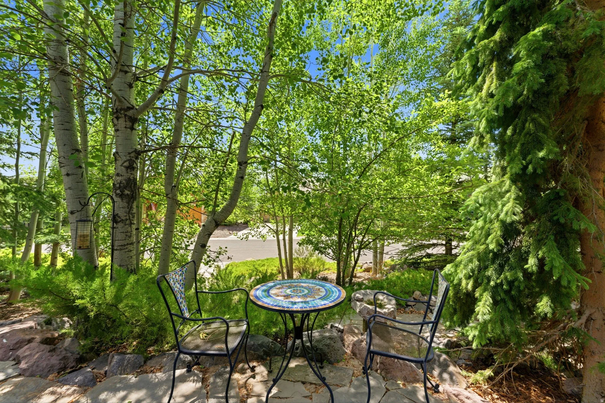 Stone patio area with mature trees and lush green foliage