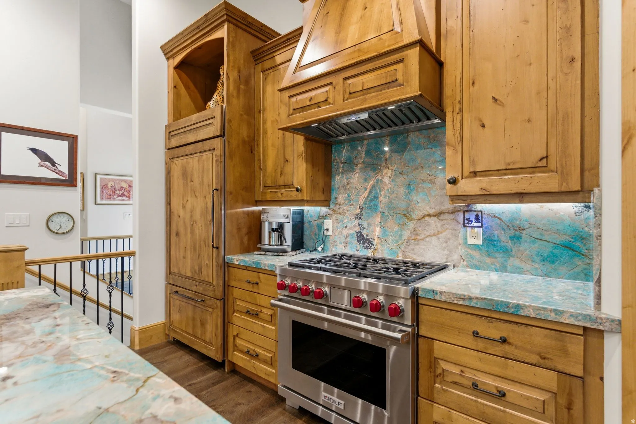 Gourmet kitchen featuring custom wood cabinetry, a stainless steel range, and unique veined countertops and backsplash