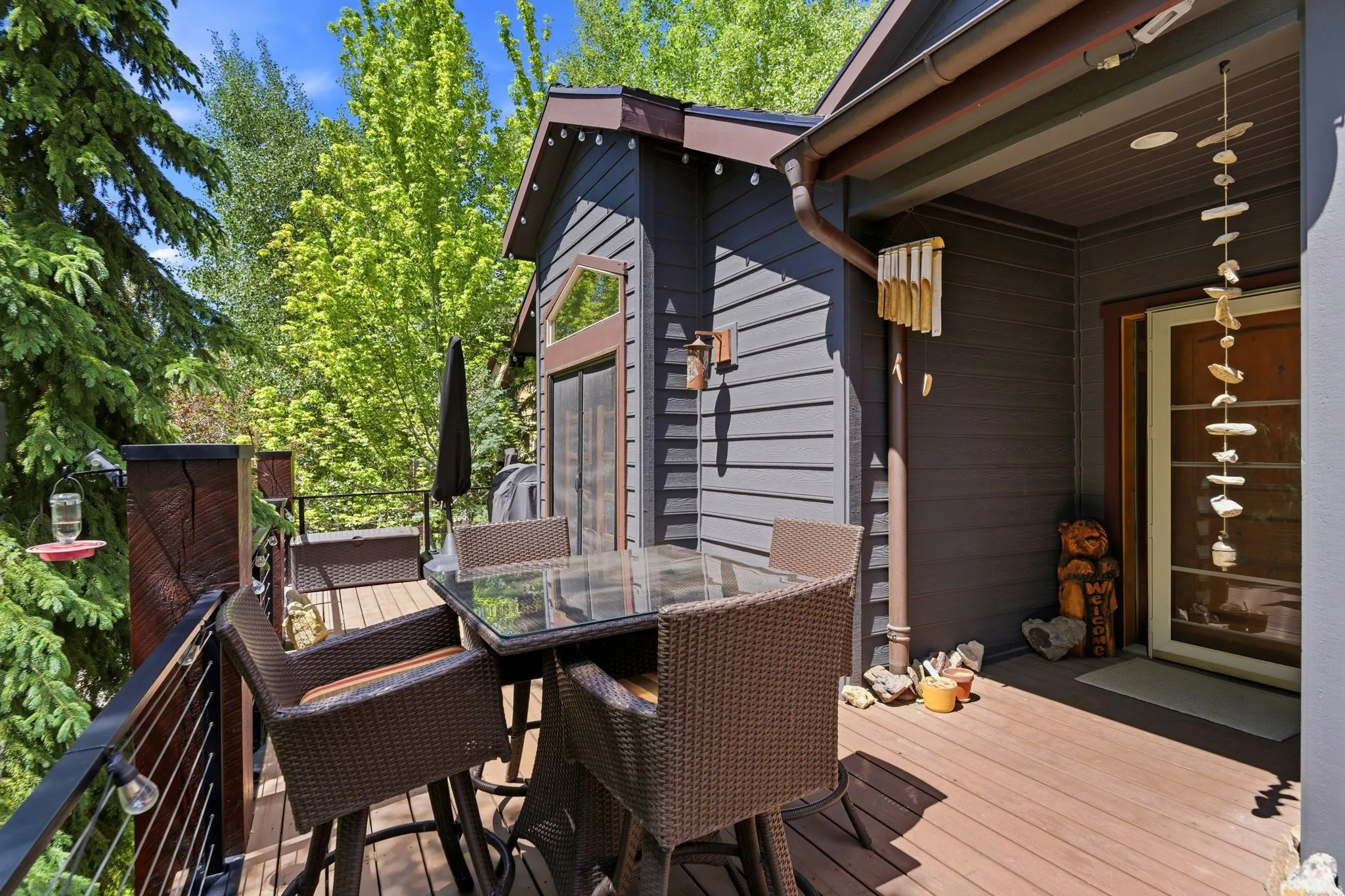 Spacious outdoor deck featuring wood-finish flooring, dark-toned siding, and a cable railing system