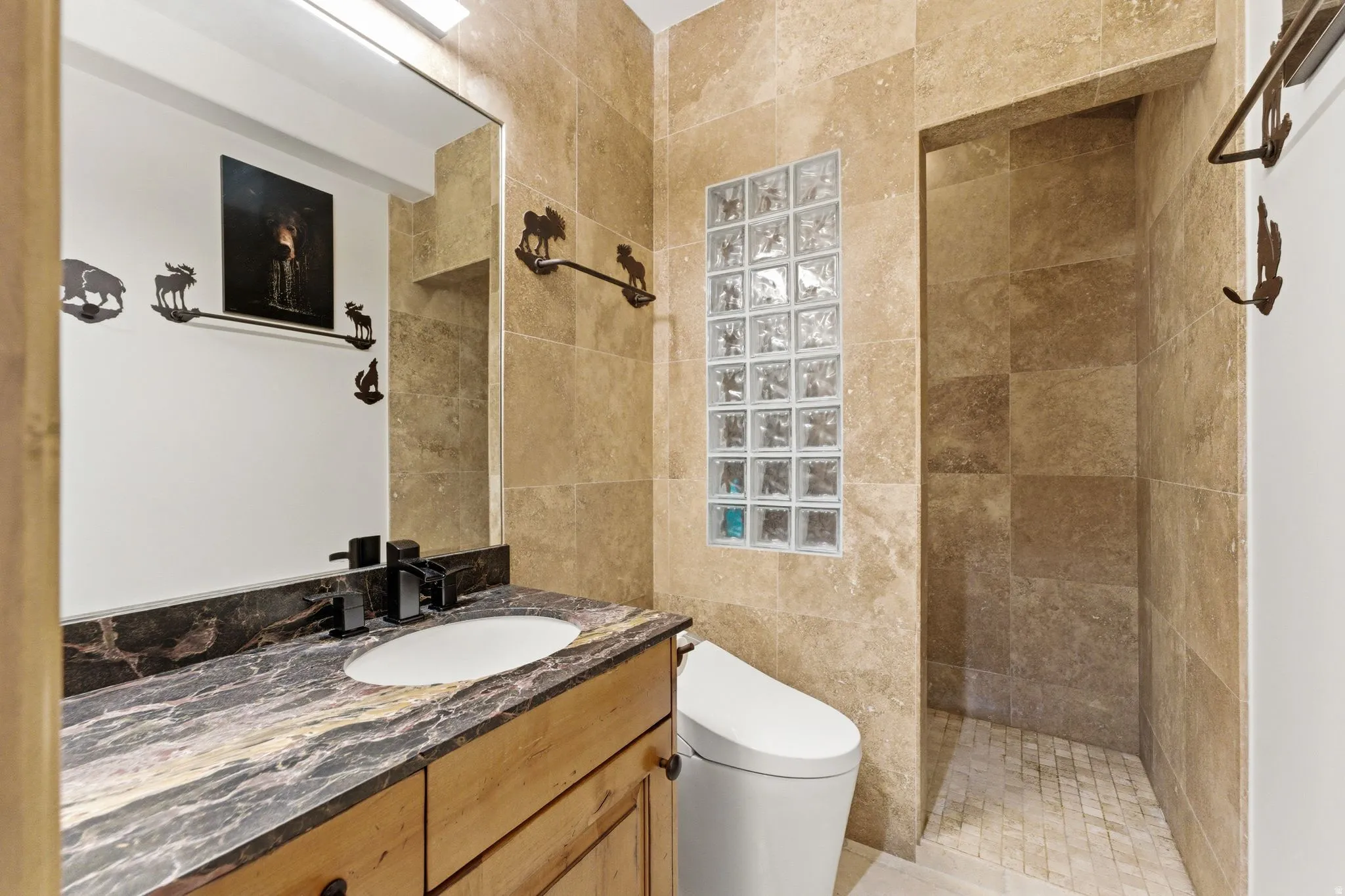 Bathroom featuring a custom wood vanity with a dark veined countertop, an undermount sink, and matte black fixtures