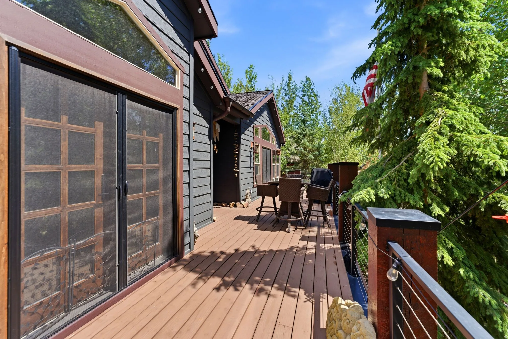 Spacious wood-finish deck with cable railing system and dark brown posts