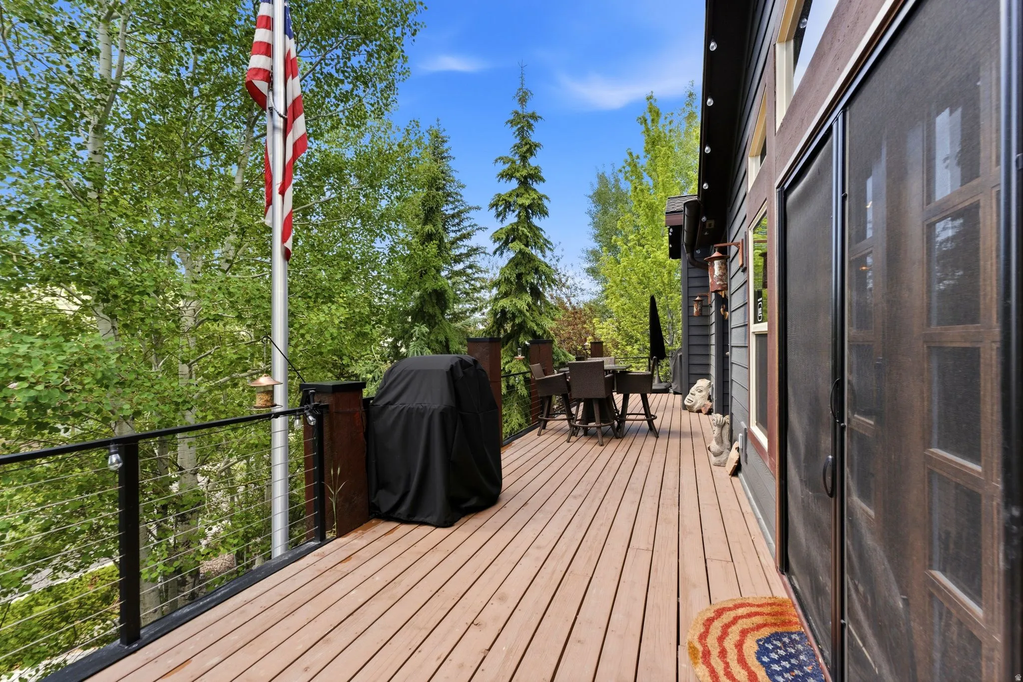 Expansive outdoor deck featuring wood-finish flooring, cable railing system, and direct access from the interior