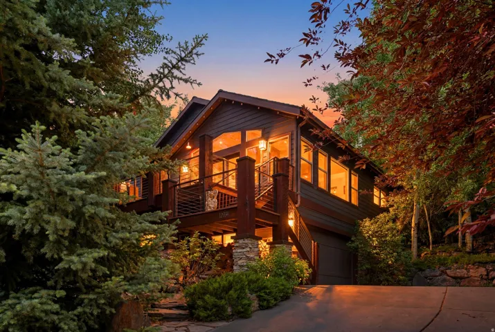 Contemporary wood-sided residence featuring multiple decks with metal railings, extensive windows, and a stone-clad foundation