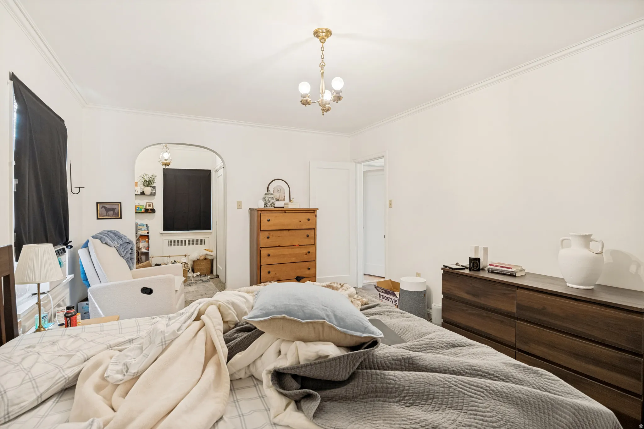 Unit 2  Bright interior room featuring a decorative brass-finish chandelier and crown molding