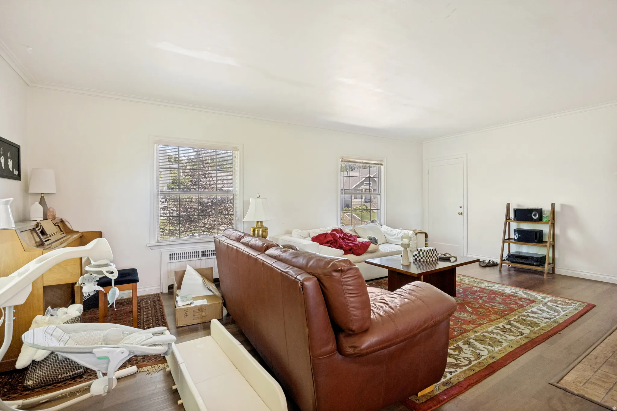 Unit 2 Spacious living area featuring wood-finish flooring, two large windows, white walls, and crown molding
