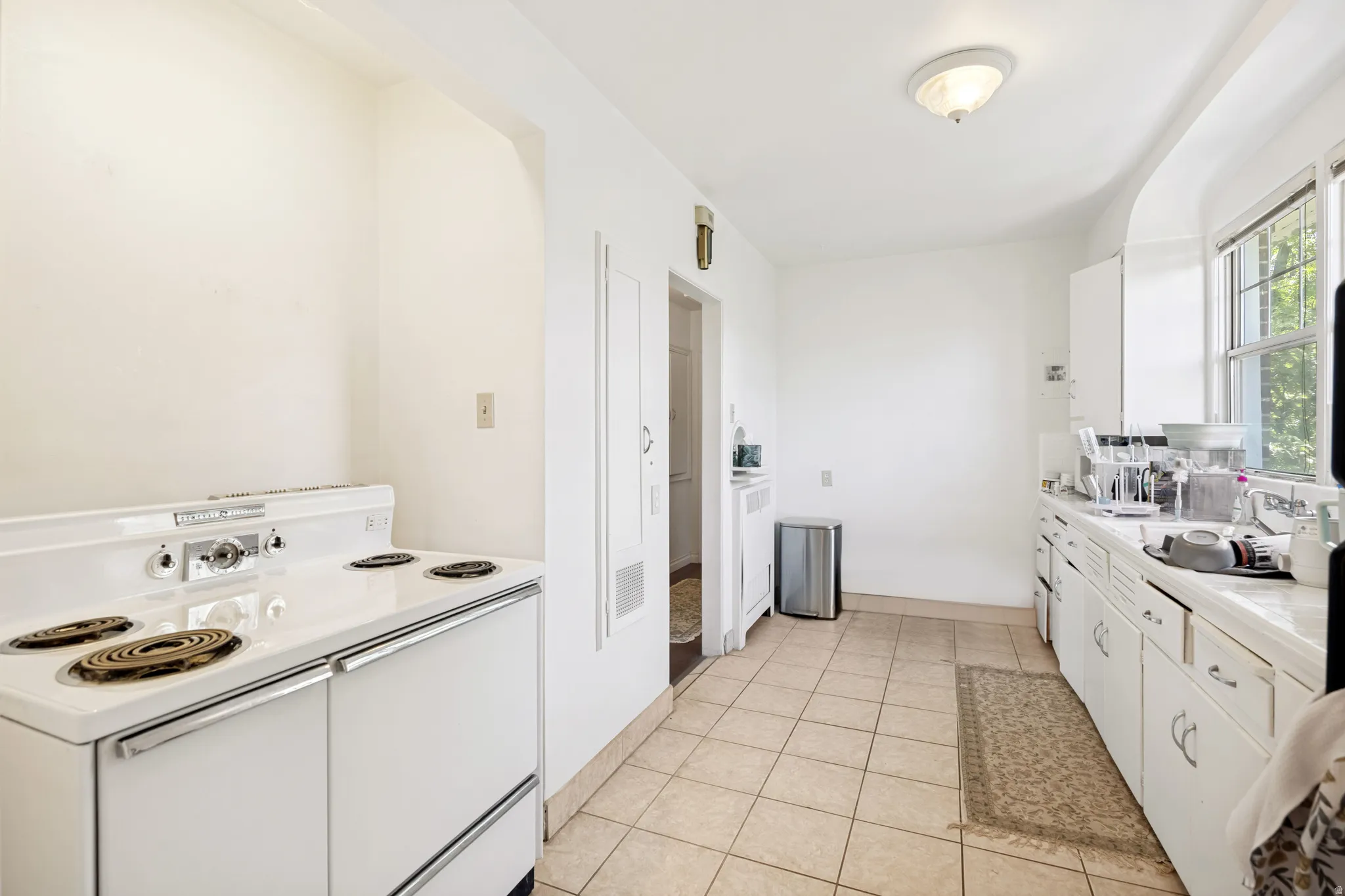 Unit 2  Kitchen with tile flooring, an electric range, built-in cabinetry, and a window