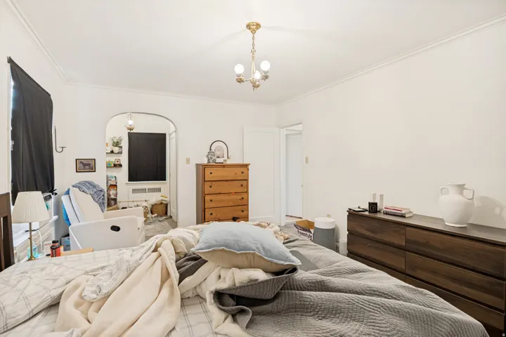 Unit 2  Bright interior room featuring a decorative brass-finish chandelier and crown molding