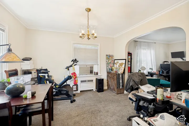 Unit 1 Carpeted interior space featuring a brass chandelier light fixture, crown molding, and an arched doorway
