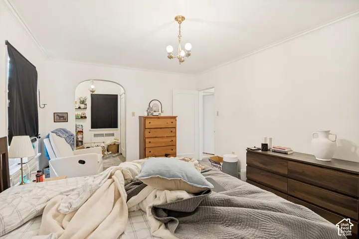 Unit 2  Bright interior room featuring a decorative brass-finish chandelier and crown molding