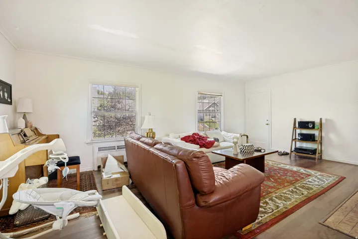 Unit 2 Spacious living area featuring wood-finish flooring, two large windows, white walls, and crown molding